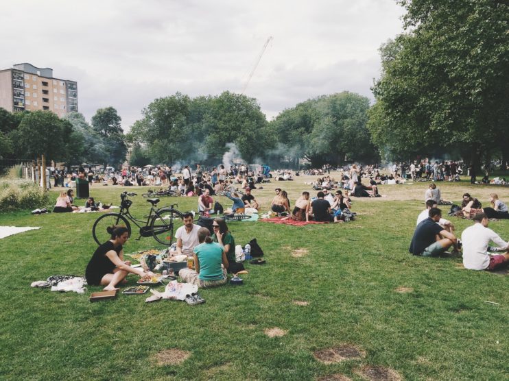 Diverse crowd of people sit and picnic in an urban park